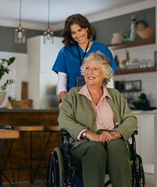 Nurse pushing elderly woman on wheelchair at home